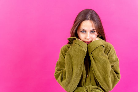 Beautiful young woman wearing warm green woolen sweater on pink background. space for textの写真素材