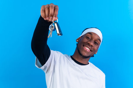Black ethnic man in white clothes on a blue background, new house keys concept