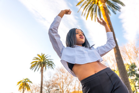 Young african woman posing in white clothes in a tropical place with palm trees at sunset, summer...