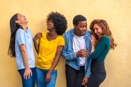 Group portrait of young multi-ethnic friends against yellow wall, international youth communityの写真素材