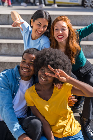 Happy multiethnic friends sitting on stairs in the city having fun, young modelsの写真素材
