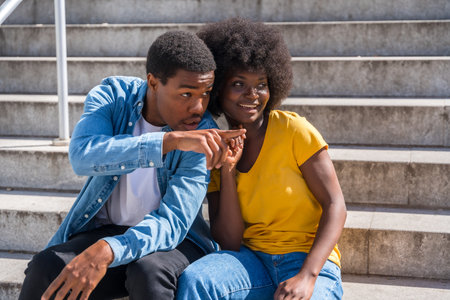 Portrait of young couple of black ethnicity sitting in the city in the sitting on the stairsの写真素材