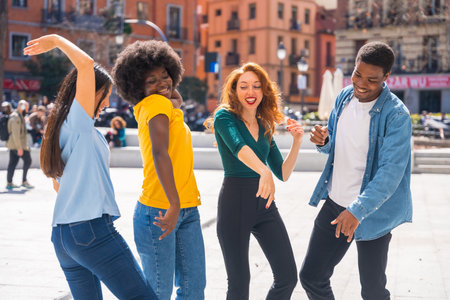 Multi-ethnic young friends dancing in a city square, group dancers having funの写真素材