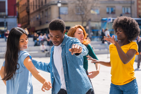 Multi ethnic young friends dancing in a city square, authentic group of diverse friends having funの写真素材