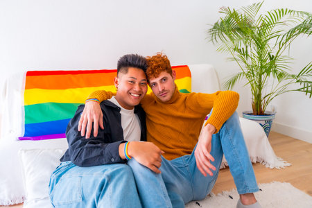 Beautiful gay couple being romantic at home together on sofa, lgbt concept