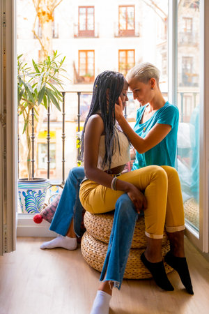 Beautiful lesbian couple in romantic pose on balcony at home, lgbt conceptの写真素材