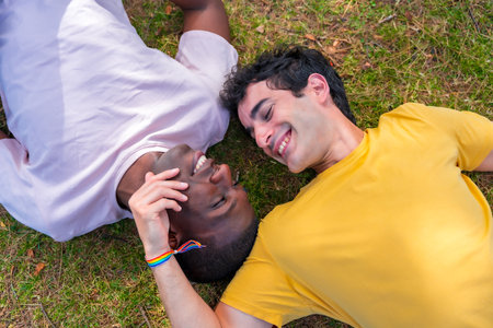 Couple of multi-ethnic men in a park, lgbt concept, lying on the grassの写真素材