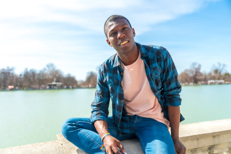 Portrait of a black ethnic man in summer by a city lake, enjoying vacationの写真素材