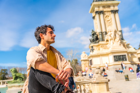 Portrait of a summer Caucasian young man next to a city sculpture, enjoying vacationの写真素材