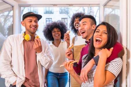Portrait group of friends eating pizza on the terrace at home laughing, lunch or dinner, lifestyleの写真素材