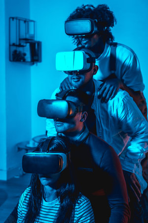 Group of young people with vr glasses in a virtual reality game in a blue light, in formation on top...