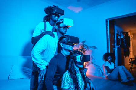 Four young people with vr glasses in a virtual reality game in a blue light, in formation on top of each other, futuristic or science, technology concept, a friend looking at them and laughingの写真素材