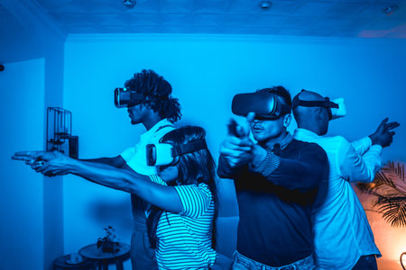 Group of young people with vr glasses in a virtual reality game in a blue light, aiming with guns, futuristic or science, technology conceptの写真素材