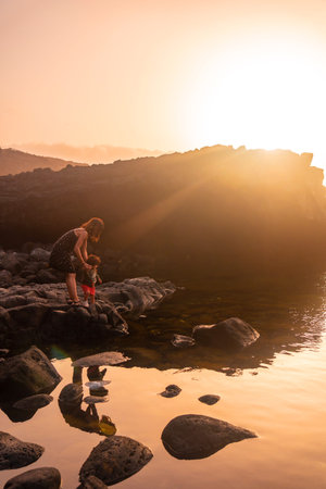 El Hierro Island. Canary Islands, mother and son in the natural pool of Charco Azul at sunset looking at the seaの写真素材