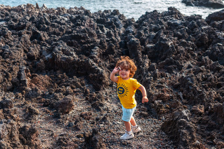 Boy playing with stones on a volcanic path on the beach of Tacoron on El Hierro, Canary Islandsの写真素材