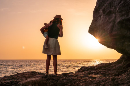Silhouette of mother and son hugging the child at sunset on the beach of Tacoron on El Hierro, Canary Islands, vacation concept, orange sunsetの写真素材