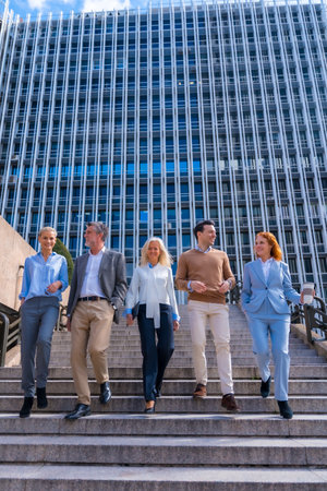 Cheerful group of coworkers outdoors in a corporate office area going down some stairs going to workの写真素材
