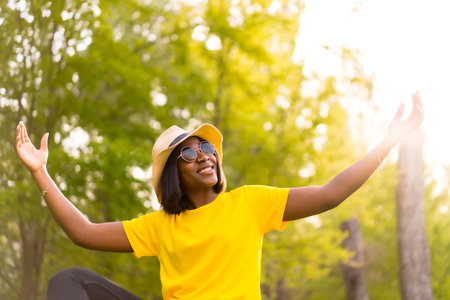 Peaceful Nature: Lifestyle Portrait of a Young Black Woman Tourist at Sunset in the Forestの写真素材
