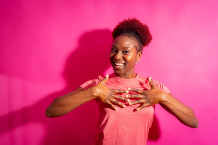 Young african american woman isolated on a pink background smiling and dancing, studio shootの写真素材