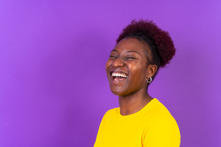 Young african american woman isolated on a purple background smiling and laughing, studio shootの写真素材