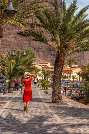 Tourist woman walking along the promenade through the town of Valle Gran Rey on La Gomera, Canary Islandsの写真素材
