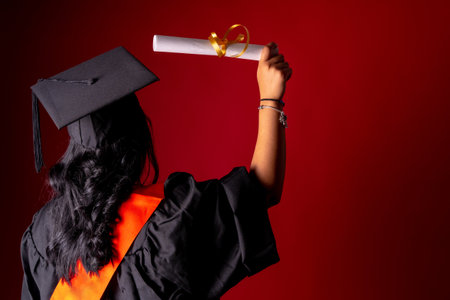 Female student in a graduation photo. End of education degree with graduate diploma. University, tunic with cap on his back with the diploma, copy spaceの写真素材