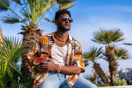 Portrait of a black ethnic man enjoy summer vacation at the beach with a watermelonの写真素材