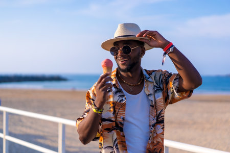 Black ethnic man enjoy summer vacation on the beach eating an ice cream having funの写真素材