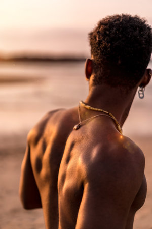 Back of muscular black ethnic man on summer vacation by the sea feeling freeの写真素材