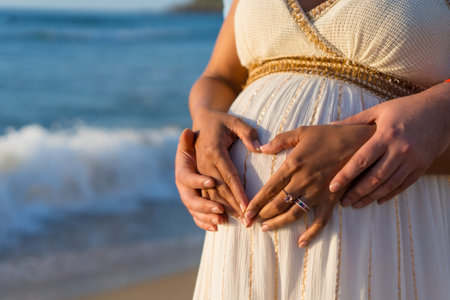 Pregnant maternity latin woman on the beach at sunset, maternity conceptの写真素材
