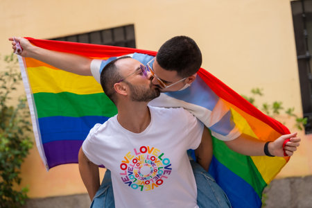 Homosexual male couple riding on top of back kissing each other at pride party with rainbow flag, lgbt concept,の写真素材