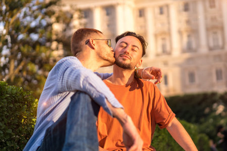 Portrait of gay newlyweds sitting in the park at sunset in a park in the city. Diversity and lgbt...
