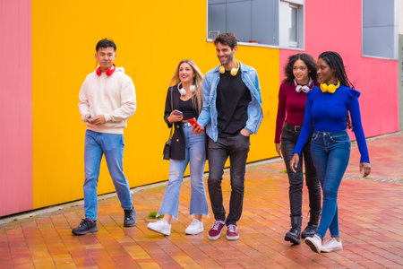 Group of multi-ethnic friends walking on university campus having fun, young millennials mobile phone technology conceptの写真素材