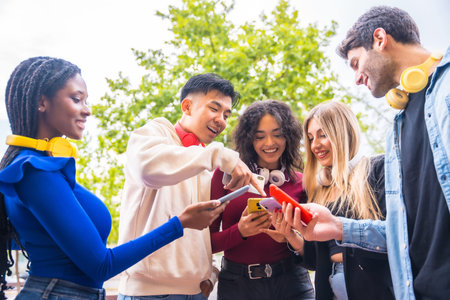 A group of young multi-ethnic teenage friends using cell phones in the city campus. Technology...