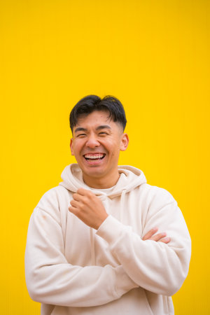 Portrait of a handsome South Korean Asian man in basic clothes smiling isolated over yellow background, smiling and having funの写真素材