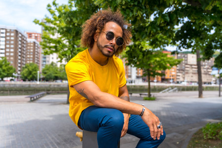 Portrait of an afro-haired man in a yellow t-shirt. Portrait in the city smiling on summer vacationの写真素材