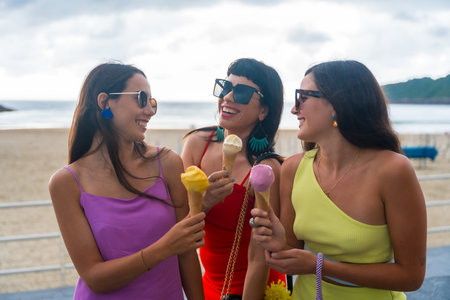 Young female friends on the beach eating ice cream on summer vacation