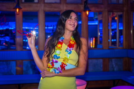 Attractive latin woman smiling at a night club party wearing heart glasses