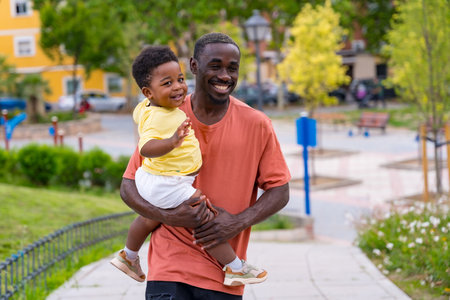 African black ethnicity father having fun with his son in playgroundの写真素材