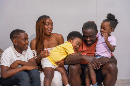 Portrait of black African ethnicity family with children on the sofa at home having funの写真素材