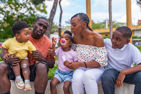 African black ethnic family with children in playground blowing soap bubblesの写真素材