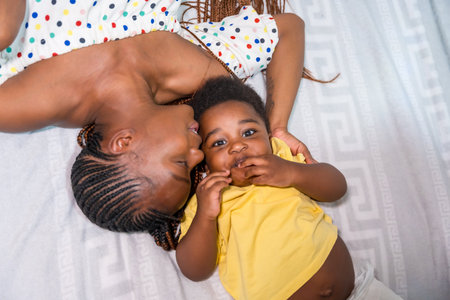 African black ethnic family mother with her little son in bedroom on bed smiling, overhead shotの写真素材