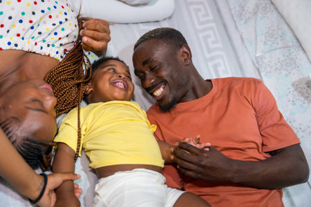 African black ethnic family with their little son in the bedroom on the bed smiling, overhead shotの写真素材