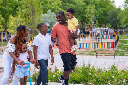 Black African ethnicity family with children at playground, smiling at school exitの写真素材