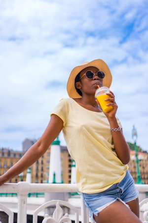 Portrait of black ethnic woman having an orange juice enjoying the summerの写真素材