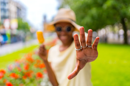 African black ethnicity woman eating a mango ice cream in the city in summer, making stopの写真素材