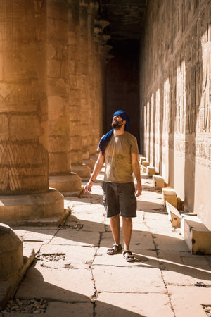 Young man in blue turban walking on the columns of the Edfu Temple near the city of Aswan. Egypt,...