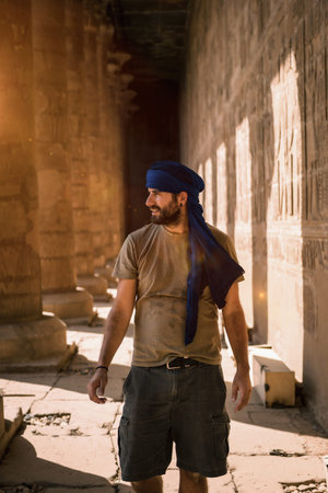 Young man in blue turban walking on the columns of the Edfu Temple near the city of Aswan. Egypt,...