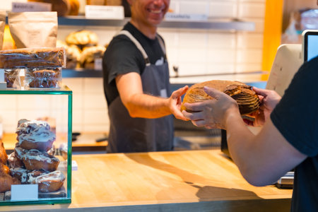 Customer in the bakery shop buying a loaf from the baker in the workshopの写真素材