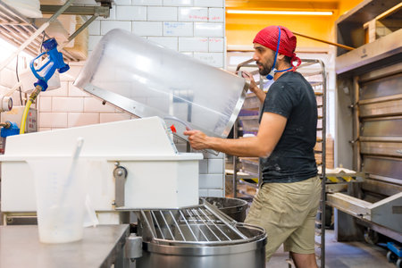Male baker of bakery in the workshop of artisan bakery preparing the sourdoughs in the kitchenの写真素材